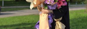 A beautiful Latina graduate, holding a bouquet in her hands, smiles with pride and joy after receiving her diploma at her graduation ceremony
